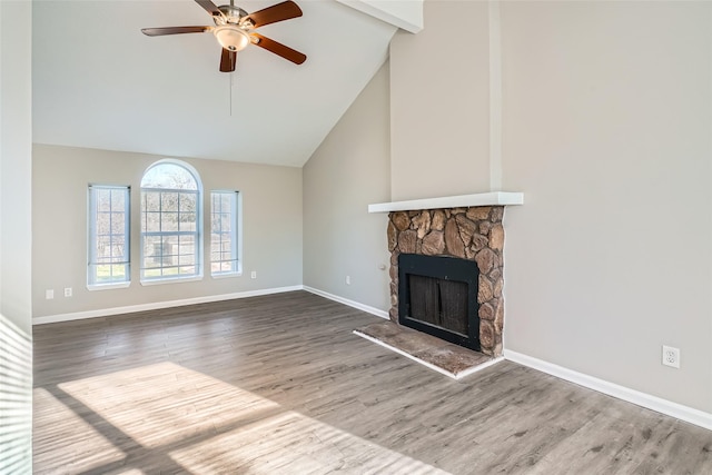 unfurnished living room with ceiling fan, beamed ceiling, high vaulted ceiling, wood-type flooring, and a fireplace