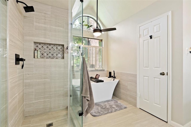 bathroom featuring ceiling fan, tile patterned flooring, lofted ceiling, independent shower and bath, and tile walls