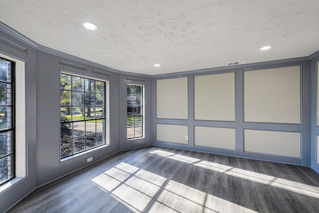 spare room featuring dark hardwood / wood-style flooring, a textured ceiling, and ornamental molding