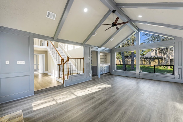 unfurnished living room with ceiling fan, lofted ceiling with beams, and hardwood / wood-style flooring