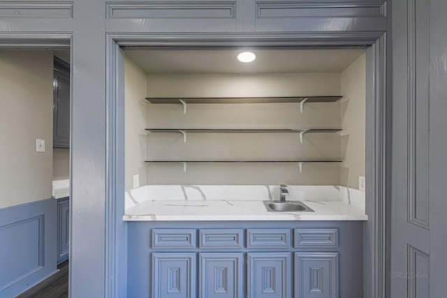 bar with light stone countertops and sink