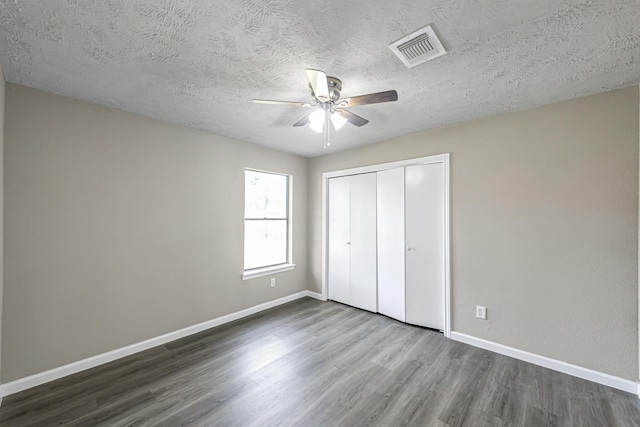 unfurnished bedroom with dark hardwood / wood-style flooring, ceiling fan, a closet, and a textured ceiling