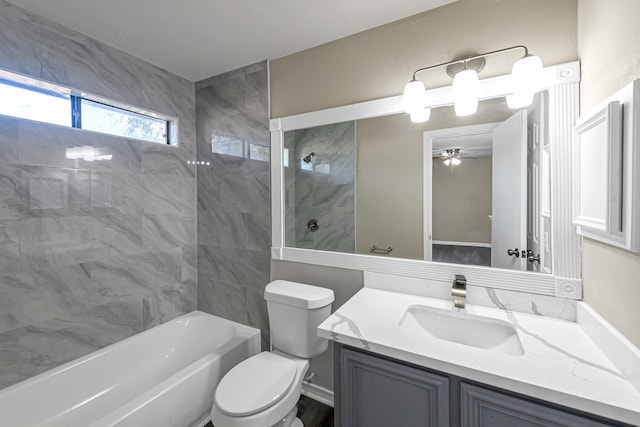 full bathroom with ceiling fan, toilet, vanity, and tiled shower / bath combo