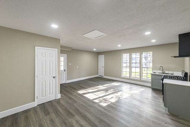 unfurnished living room featuring a textured ceiling, sink, and dark wood-type flooring