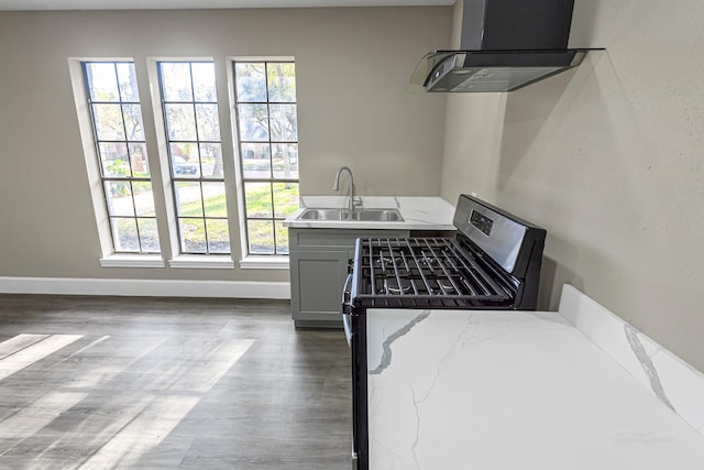 kitchen with black gas range, sink, a wealth of natural light, and exhaust hood