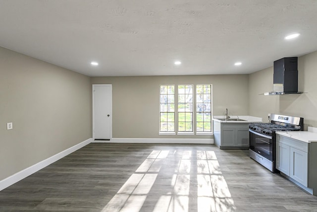 kitchen with stainless steel gas stove, light hardwood / wood-style floors, wall chimney exhaust hood, and sink