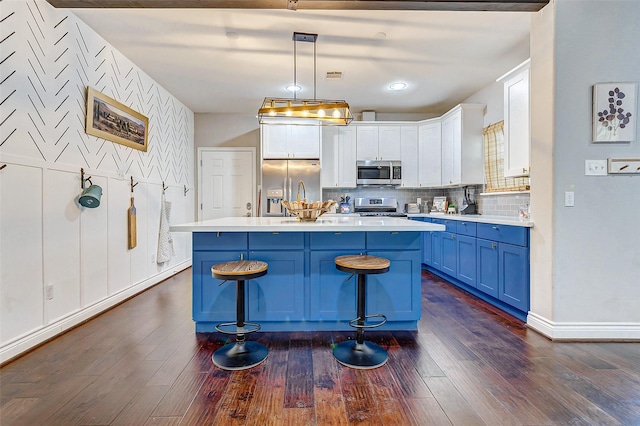 kitchen featuring a center island, a kitchen breakfast bar, blue cabinets, decorative light fixtures, and stainless steel appliances