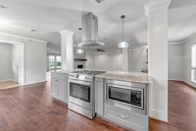 kitchen with light stone countertops, hanging light fixtures, island exhaust hood, appliances with stainless steel finishes, and ceiling fan