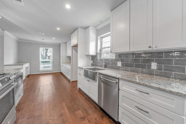 kitchen with sink, stainless steel appliances, white cabinetry, and ornamental molding