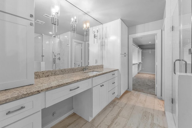 bathroom with an enclosed shower, vanity, a chandelier, and hardwood / wood-style flooring