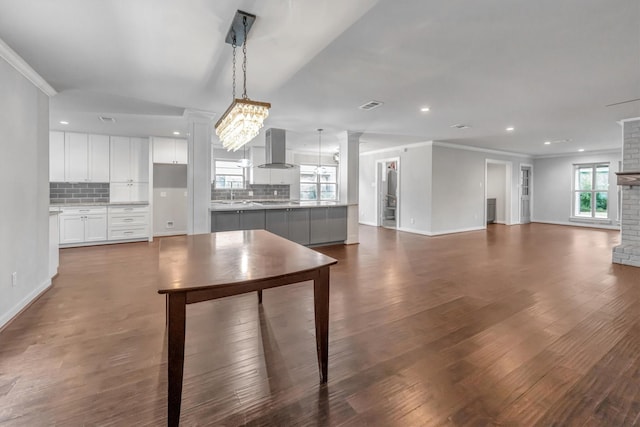 kitchen with hanging light fixtures, tasteful backsplash, an inviting chandelier, white cabinets, and ventilation hood