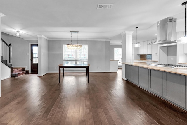 kitchen featuring island range hood, crown molding, light stone countertops, pendant lighting, and tasteful backsplash