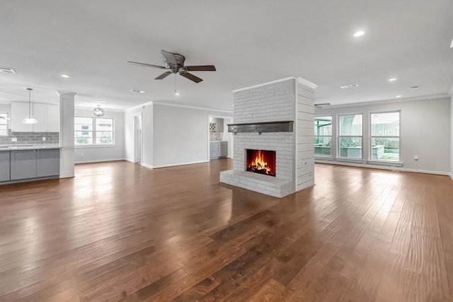 unfurnished living room featuring a fireplace, ceiling fan, ornamental molding, and hardwood / wood-style flooring