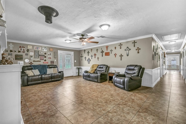 tiled living room with ceiling fan, a textured ceiling, and ornamental molding