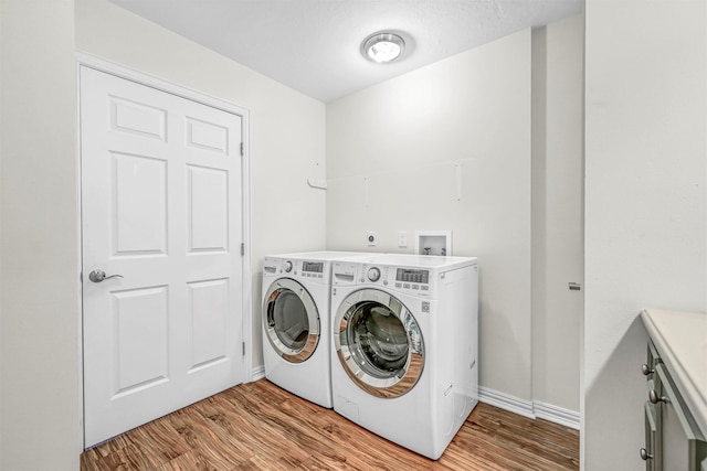 washroom featuring cabinets, independent washer and dryer, and light hardwood / wood-style floors