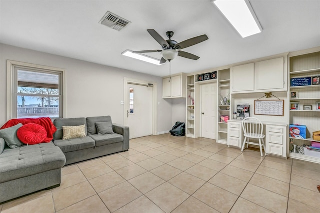 living room featuring light tile patterned floors, built in desk, and ceiling fan