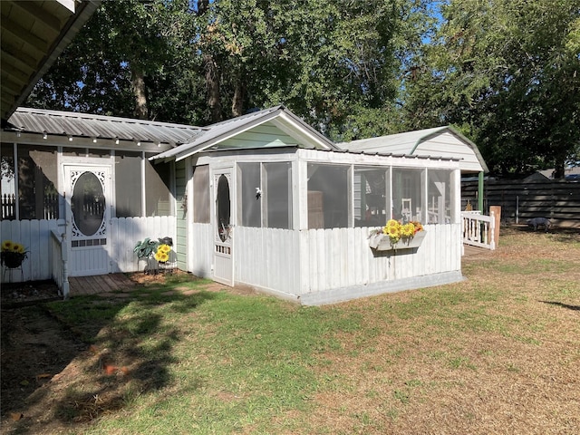 back of property with a sunroom and a yard