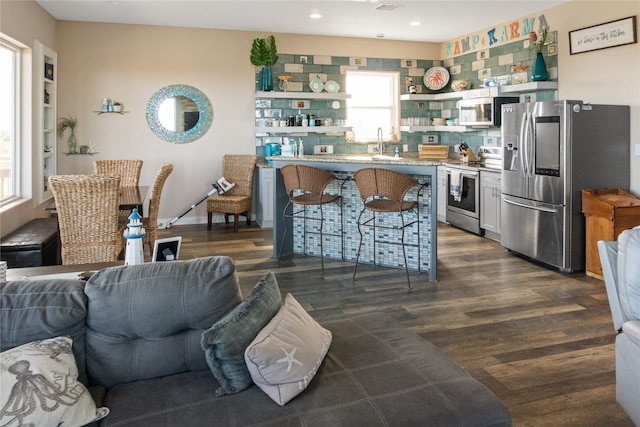 kitchen with a kitchen breakfast bar, dark hardwood / wood-style floors, sink, and stainless steel appliances