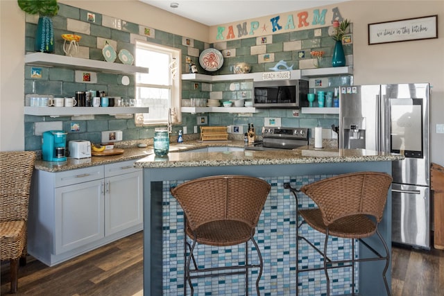 kitchen with light stone countertops, appliances with stainless steel finishes, a breakfast bar, sink, and white cabinetry