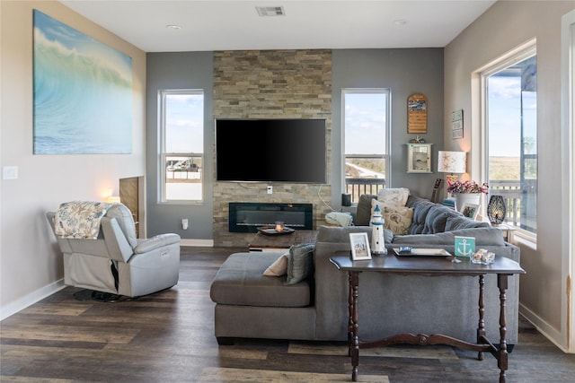 living room with a stone fireplace and dark hardwood / wood-style floors