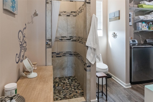 bathroom featuring washer / clothes dryer, toilet, hardwood / wood-style floors, and tiled shower