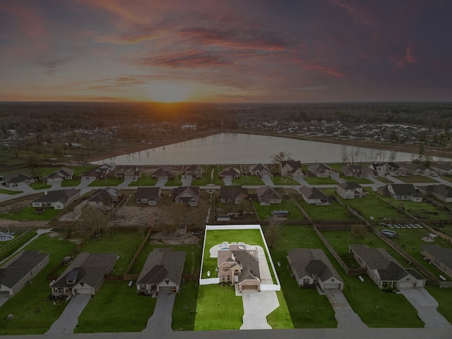 aerial view at dusk featuring a water view