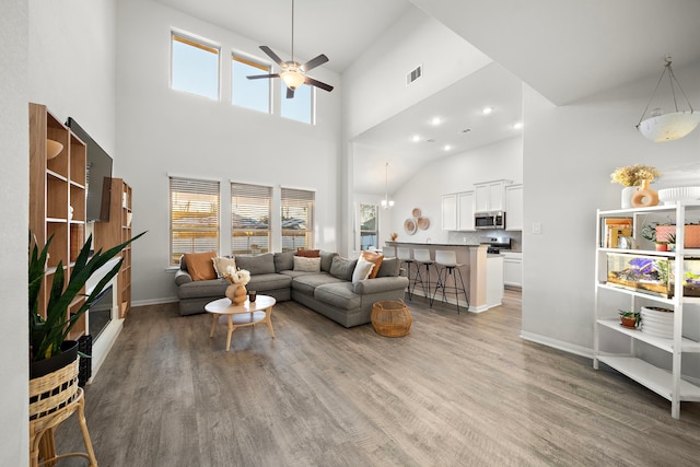 living room with ceiling fan, a towering ceiling, and dark hardwood / wood-style flooring