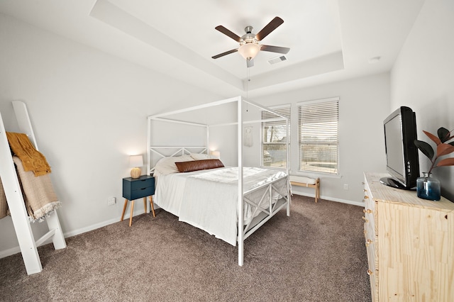 carpeted bedroom with a raised ceiling and ceiling fan