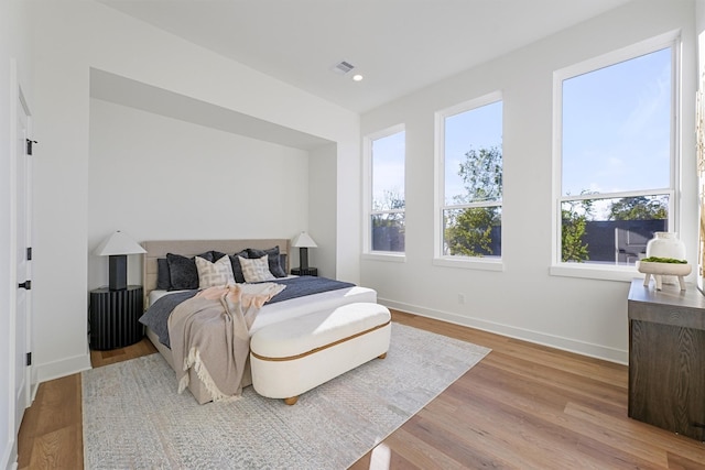 bedroom with light hardwood / wood-style floors and multiple windows