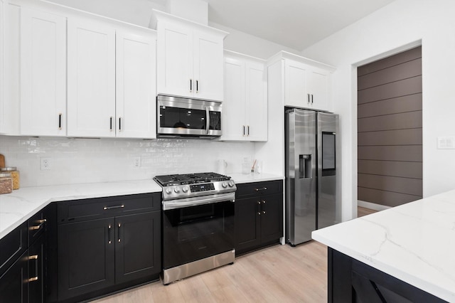 kitchen with decorative backsplash, light hardwood / wood-style flooring, white cabinets, and appliances with stainless steel finishes