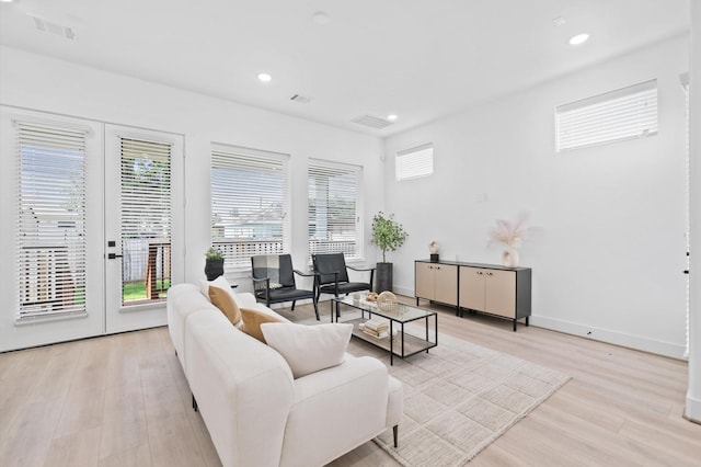 living room featuring a wealth of natural light, french doors, and light hardwood / wood-style floors