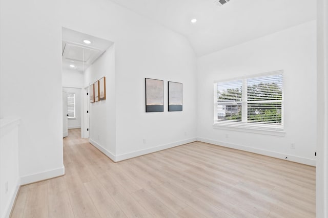 unfurnished room featuring a healthy amount of sunlight, vaulted ceiling, and light hardwood / wood-style floors