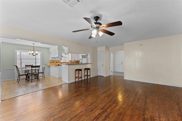 living room featuring a textured ceiling, light hardwood / wood-style floors, and ceiling fan with notable chandelier