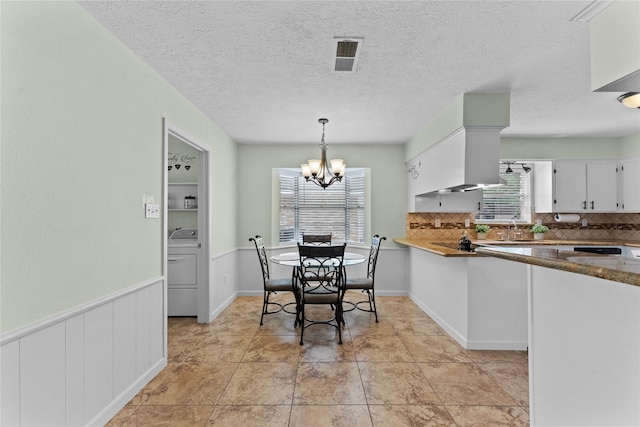 tiled dining room with washer / clothes dryer, sink, plenty of natural light, and an inviting chandelier