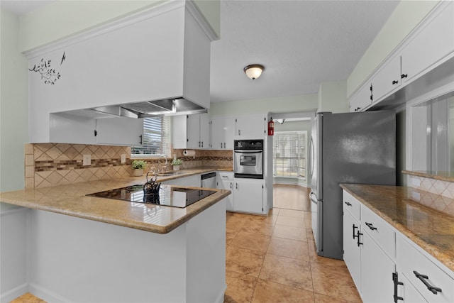 kitchen with stainless steel appliances, light tile patterned floors, backsplash, kitchen peninsula, and white cabinets