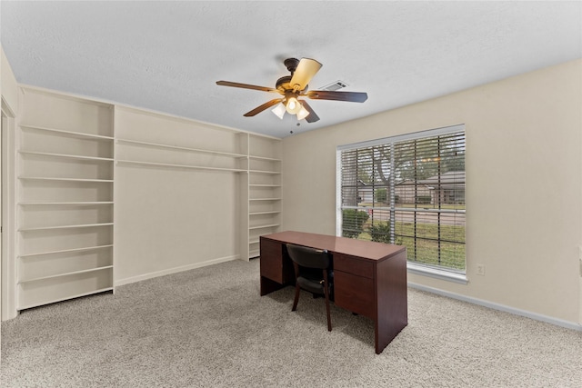 carpeted home office with built in shelves, a textured ceiling, and ceiling fan