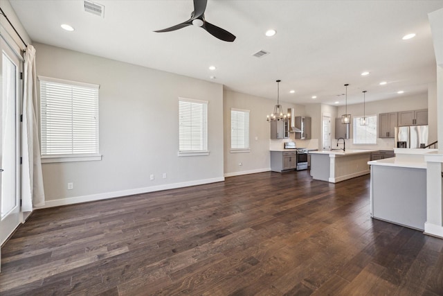 unfurnished living room featuring dark hardwood / wood-style floors, sink, and ceiling fan with notable chandelier