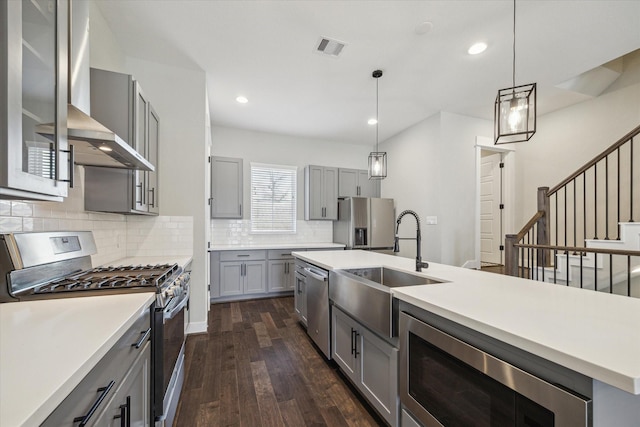 kitchen featuring backsplash, dark hardwood / wood-style flooring, stainless steel appliances, sink, and decorative light fixtures