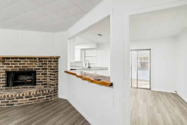 unfurnished living room with a fireplace, light hardwood / wood-style floors, and sink