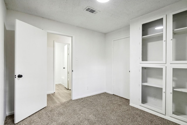 unfurnished bedroom featuring two closets, carpet floors, and a textured ceiling