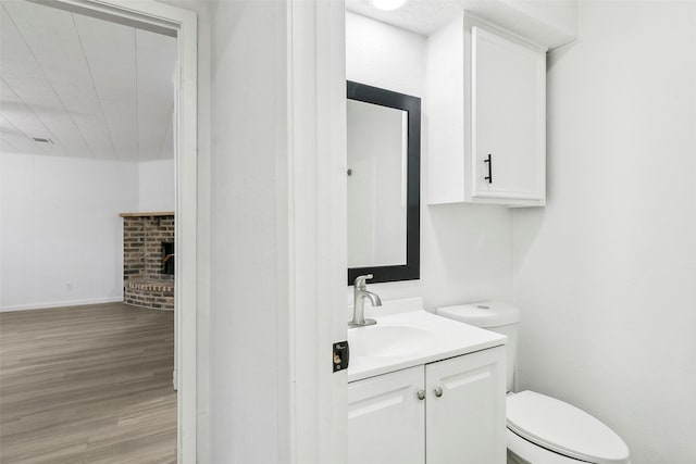 bathroom featuring a fireplace, toilet, vanity, and hardwood / wood-style flooring