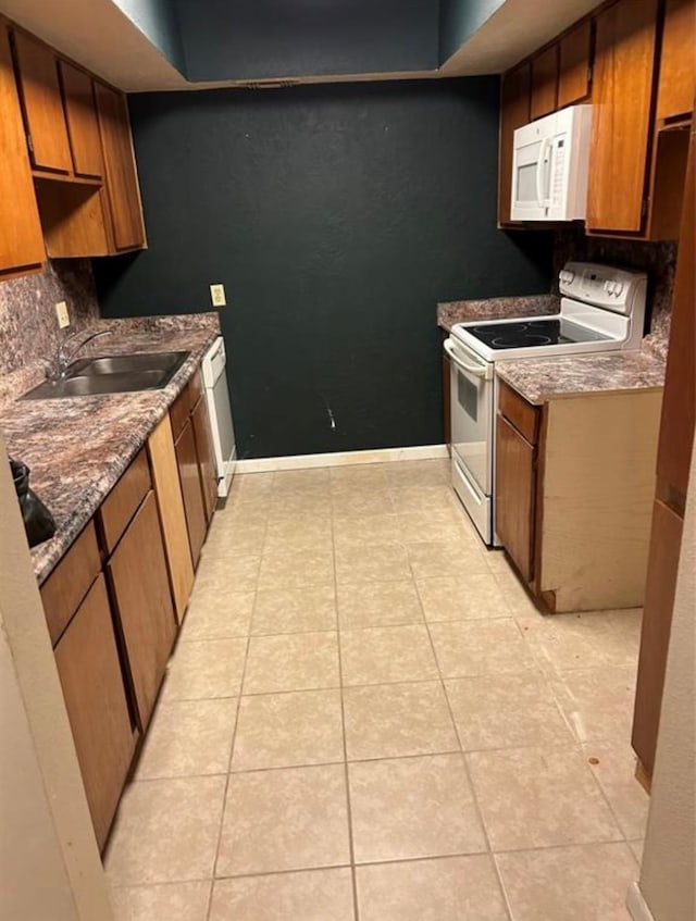 kitchen featuring white appliances, sink, and light tile patterned floors