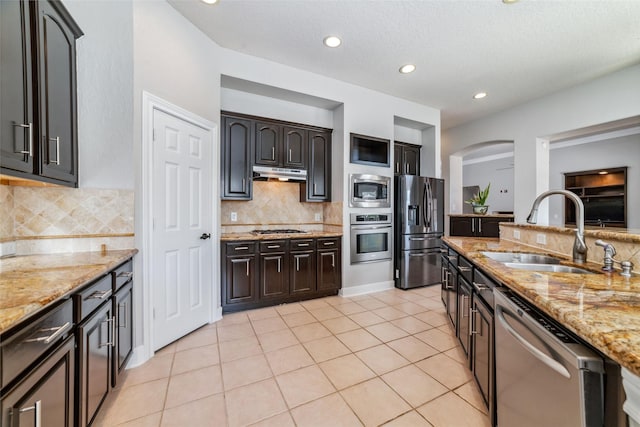 kitchen with light stone countertops, appliances with stainless steel finishes, backsplash, and sink