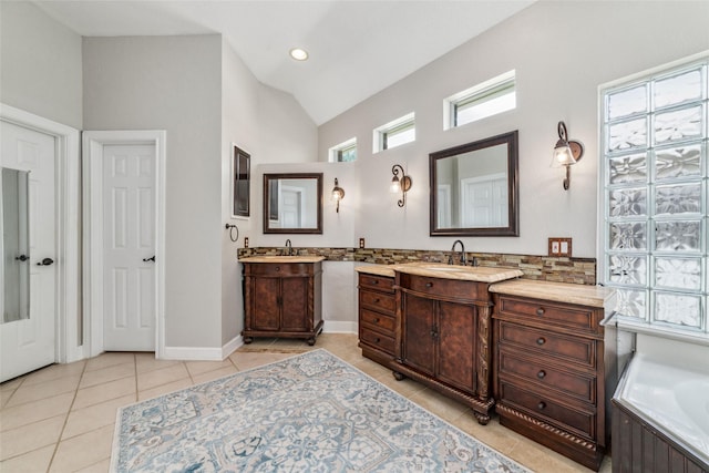 bathroom featuring tile patterned floors, vanity, a bathing tub, and lofted ceiling