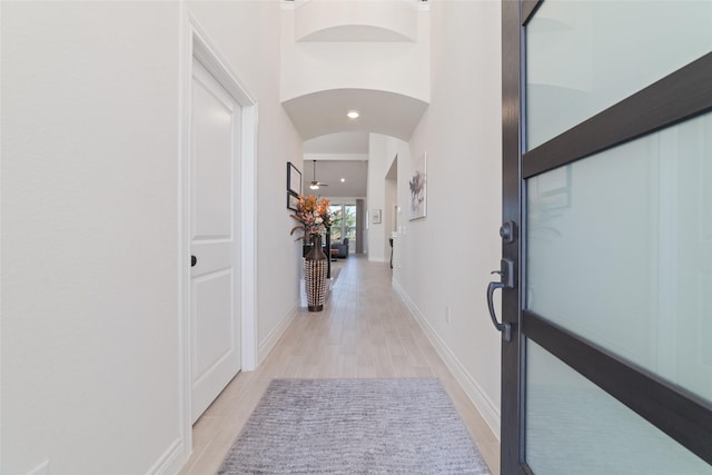 hall with light hardwood / wood-style flooring and a high ceiling