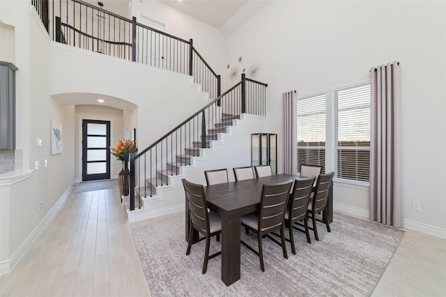 dining space featuring a high ceiling and light hardwood / wood-style flooring