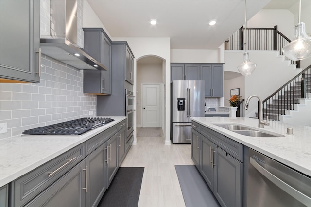 kitchen with gray cabinetry, sink, wall chimney exhaust hood, tasteful backsplash, and appliances with stainless steel finishes