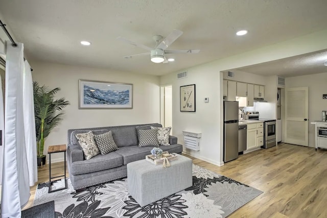 living room with ceiling fan, light hardwood / wood-style flooring, and sink