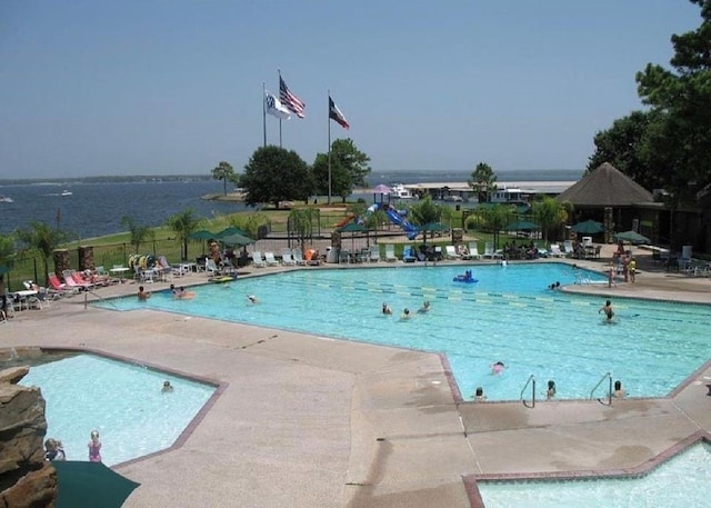 view of pool featuring a water view and a patio