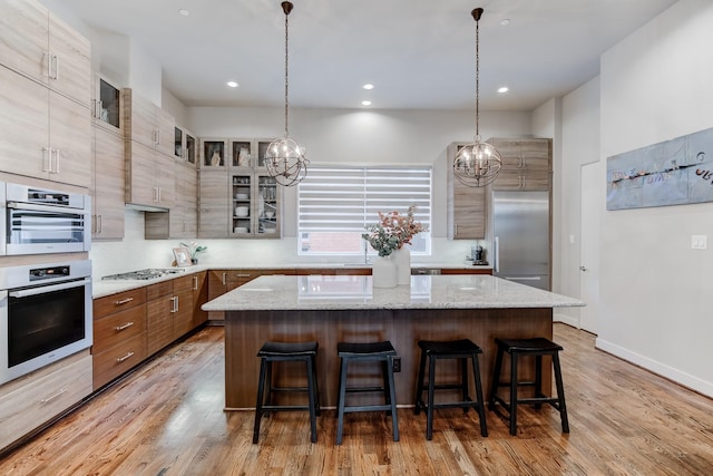 kitchen with a kitchen breakfast bar, a chandelier, a kitchen island, and stainless steel appliances